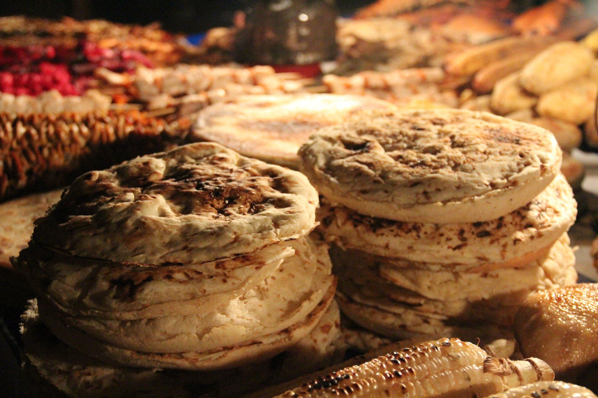 Stacks of Zanzibari flatbread and grilled corn on the cob at a Forodhani night food market stall in Stone Town, Zanzibar.
